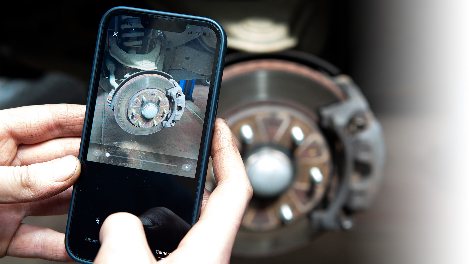 Close up of technician using app to take a picture of a vehicles brakes